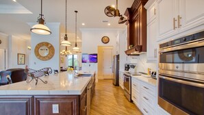 A spacious kitchen with a large island, stainless steel appliances, and pendant lighting. - Villa Paradise (Cape Coral)