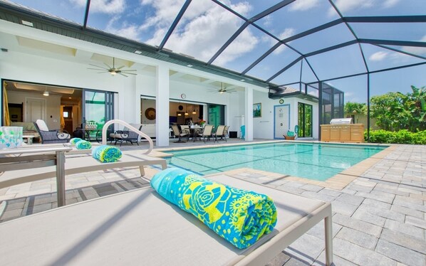 A pool area with lounge chairs and a covered patio. - Villa Paradise (Cape Coral)