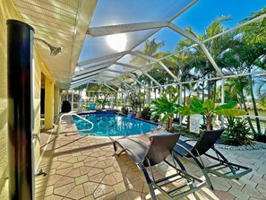 Un espace piscine intérieur offrant une vue dégagée sur le bassin, des chaises longues et la végétation tropicale environnante.
