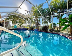 Une piscine intérieure à l’eau d’un bleu cristallin, entourée de plantes tropicales et dotée d’une structure de plafond en verre.