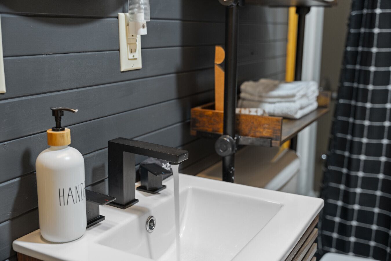 A bathroom with a white sink, a soap dispenser, and a towel rack.