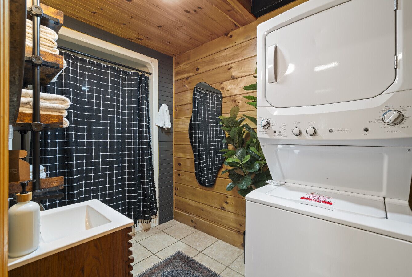A laundry area with a washing machine, a sink, and a towel rack.