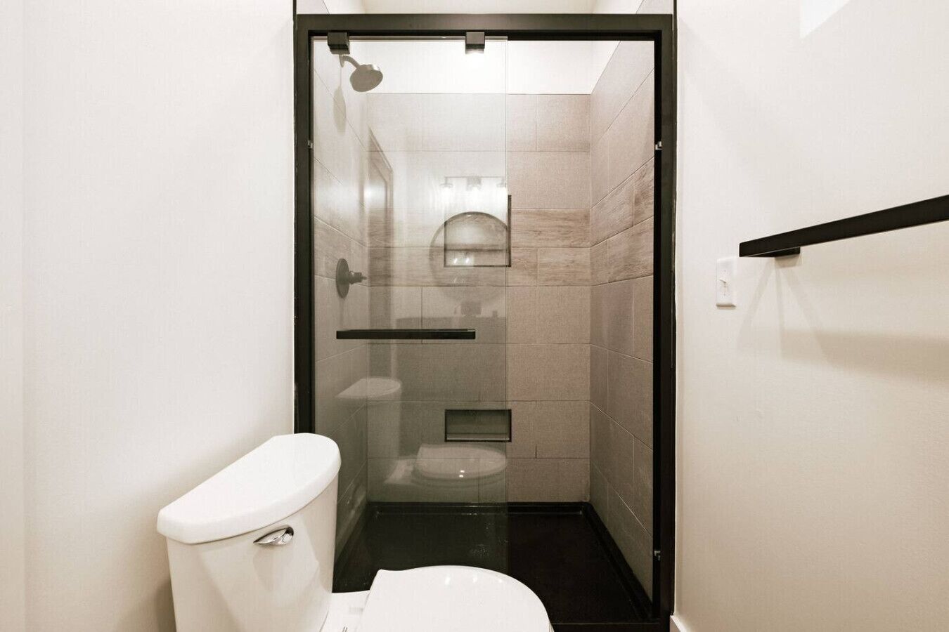 Un baño pequeño con ducha de mampara, inodoro y lavamanos.