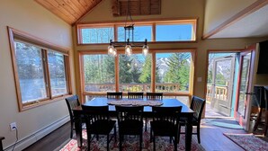 A dining area with a wooden table and chairs, large windows with a view of trees, and a ceiling fan. - Mwp25 Updated 3 bed 3 Bath Condo With Mountain ski Slope Views in Bretton Woods (Bretton Woods)