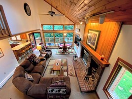 Una sala de estar acogedora con chimenea, asientos cómodos y ventanas amplias con vista a una terraza.