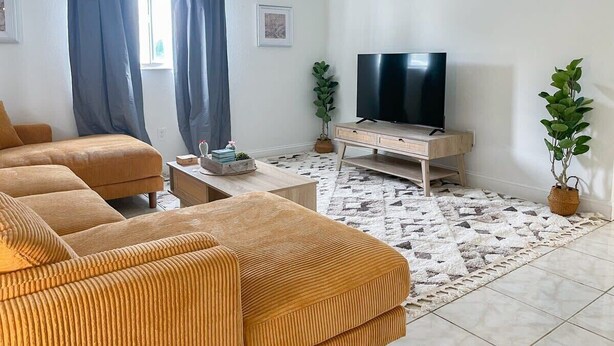 Un salon comprenant un ensemble de canapés, une table basse, un meuble pour la télévision et un tapis à motifs.