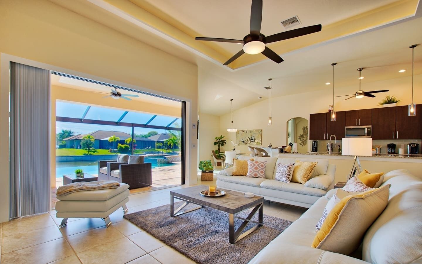 A spacious living area with a large sofa, a coffee table, and a view of a swimming pool and outdoor patio.