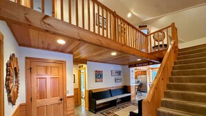 Eine Holztreppe führt zu einer zweiten Etage, ein Schild für den Familien-Skibereich, eine Bank und ein Küchenbereich sind zu sehen.