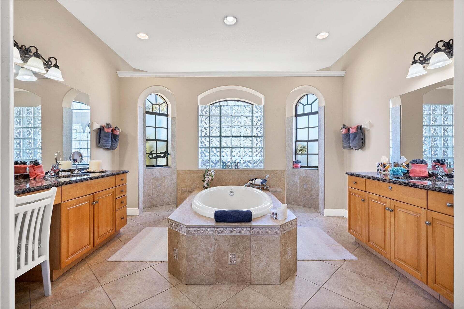 Ein geräumiges Badezimmer mit einer großen Badewanne, zwei Waschbecken und drei großen Fenstern mit Verzierglas.