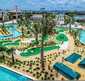 Campo de golf con varios hoyos, palmeras y una zona de piscina.