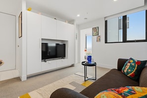 Ein modernes Wohnzimmer mit Flachbildfernseher, einer Couch, einem Couchtisch und einem Fenster mit Blick.