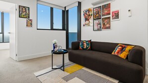 Una sala de estar moderna con un sofá marrón, una mesita auxiliar y un ventanal grande.