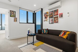 Ein modernes Wohnzimmer mit einem braunen Sofa, einem kleinen Beistelltisch und einem großen Fenster.