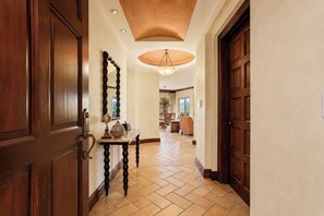 A hallway with a wooden door, a table with decorative items, and a ceiling light fixture.