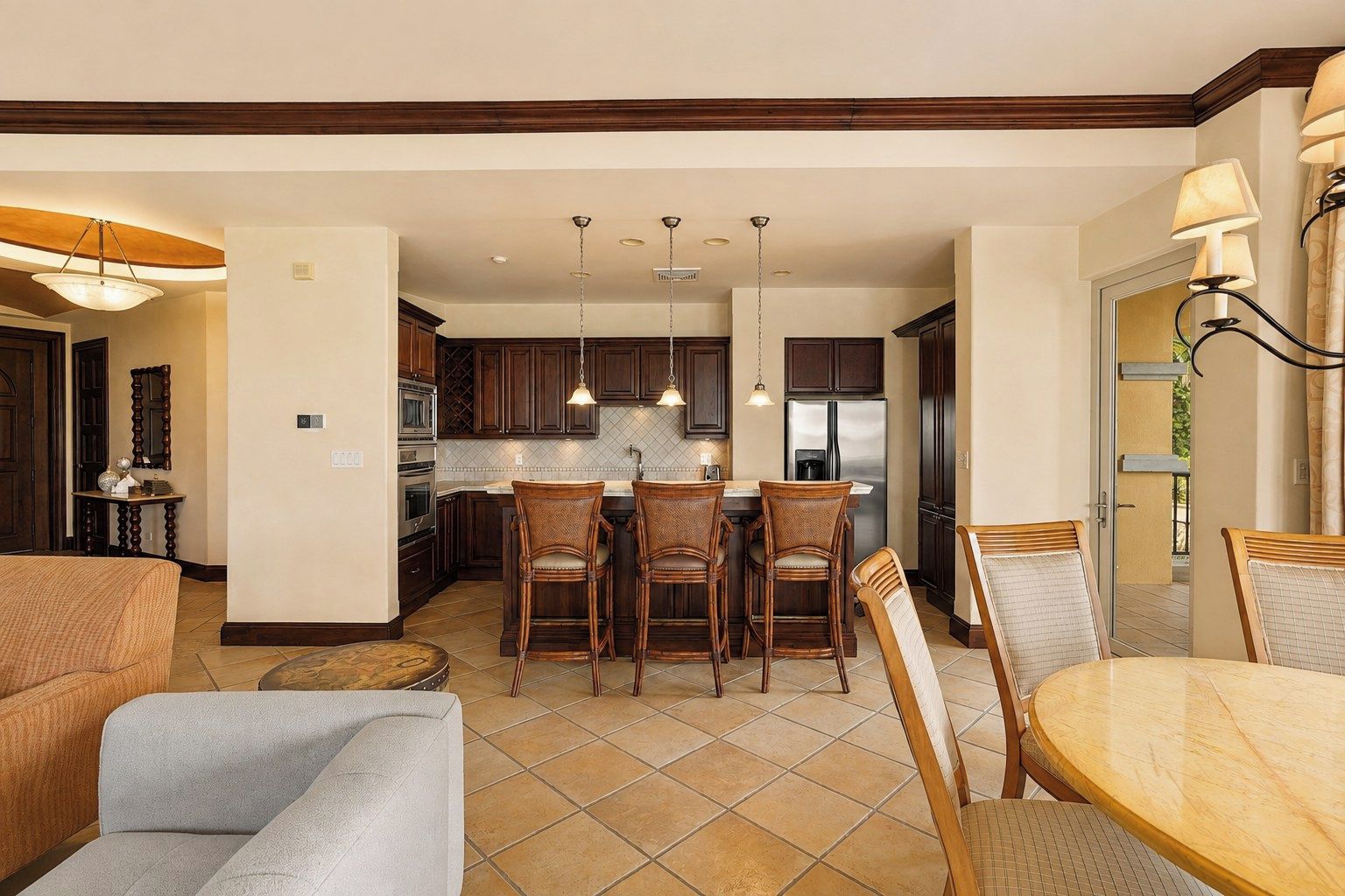A modern kitchen with dark wooden cabinets, a central island with bar stools, and stainless steel appliances.
