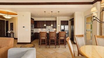 A modern kitchen with dark wooden cabinets, a central island with bar stools, and stainless steel appliances.