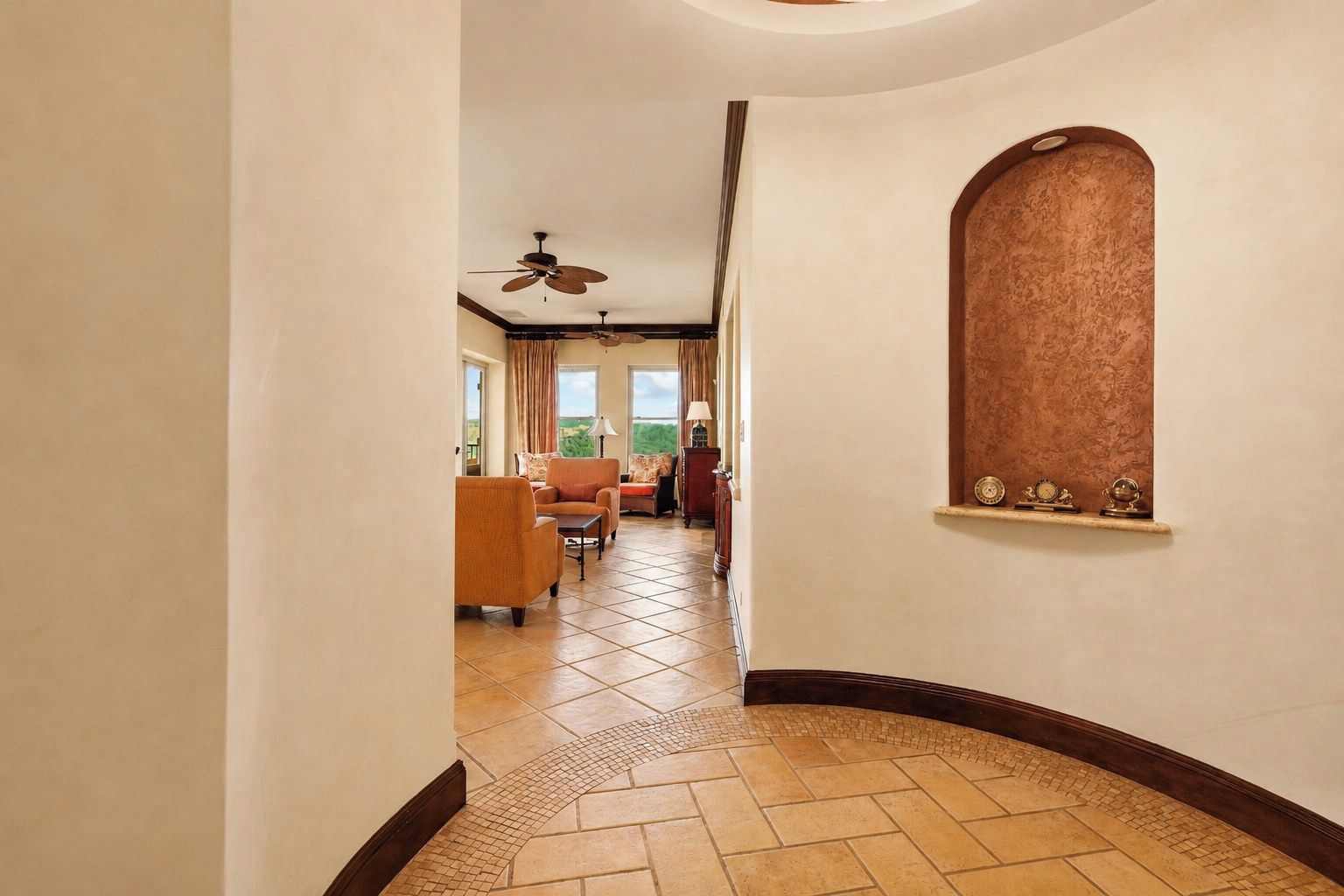 A hotel hallway with a curved wall, a ceiling fan, and a view of the outdoors.