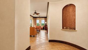 A hotel hallway with a curved wall, a ceiling fan, and a view of the outdoors.