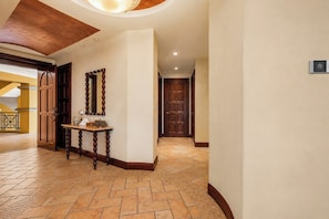 A hallway with a wooden door, a mirror, and a small table with books.