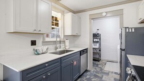 A kitchen with white cabinets, a sink, a dishwasher, and a stove. - Lazy Bear Meadow | Dog-Friendly Cabin with Fenced Yard, Hot Tub & Putting Green (Sevierville)