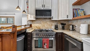 A kitchen with a gas stove, oven, microwave, and wooden cabinets. - Sedona Cowboy Retreat, Hot Tub, Game Room, Saloon (Sedona)