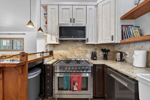 A kitchen with a gas stove, oven, microwave, and wooden cabinets. - Sedona Cowboy Retreat, Hot Tub, Game Room, Saloon (Sedona)