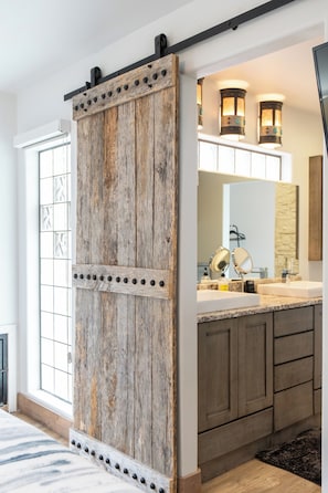 A kitchen with a rustic wooden sliding door, a built-in island with a sink, and pendant lighting. - Sedona Cowboy Retreat, Hot Tub, Game Room, Saloon (Sedona)