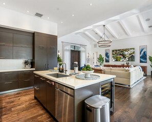 A modern kitchen with dark cabinets, a central island, and a stainless steel dishwasher. - Private Waterfront Luxury Villa Resort-style Living Privacy (Fort Lauderdale)