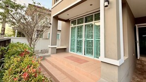 Um edifício moderno de dois andares, com varanda, amplas portas de vidro e área de entrada com azulejos.