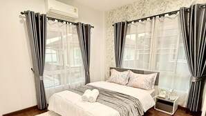 Quarto com cama grande, duas mesas de cabeceira e janela com cortinas.