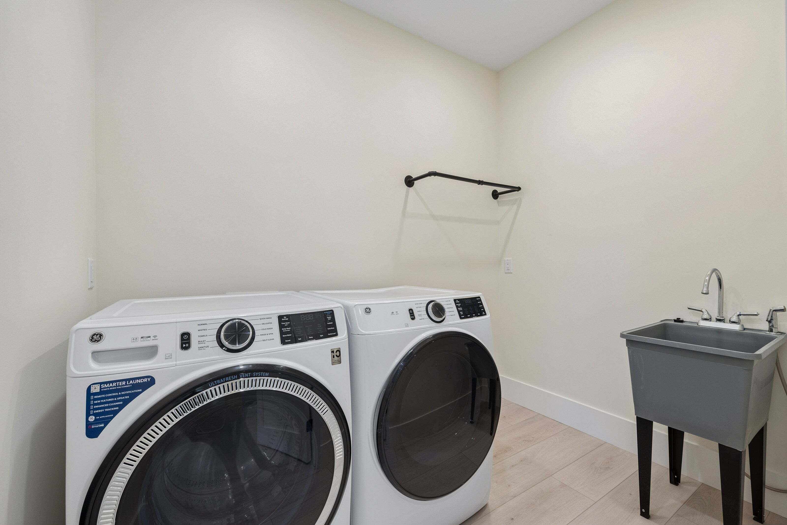 A laundry area with two front-loading washing machines and a small sink.