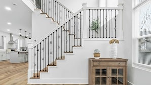 A staircase with black balusters, a wooden cabinet with glass doors, and a potted plant on the landing.