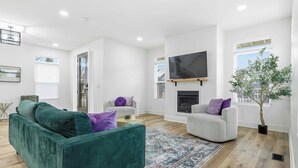 A modern living room with a green sofa, a grey armchair, and a fireplace.