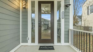 A house with a front door, a mailbox, and a number sign.