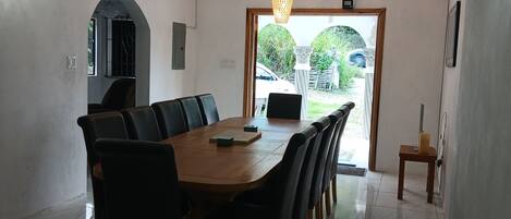 A dining area with a wooden table and black chairs, a chandelier, and a view of the outside.