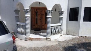A building with a wooden door, white columns, and a gravel driveway.