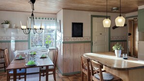 Une cuisine chaleureuse avec des meubles en bois, une table à manger pour quatre personnes et des suspensions au-dessus du comptoir.