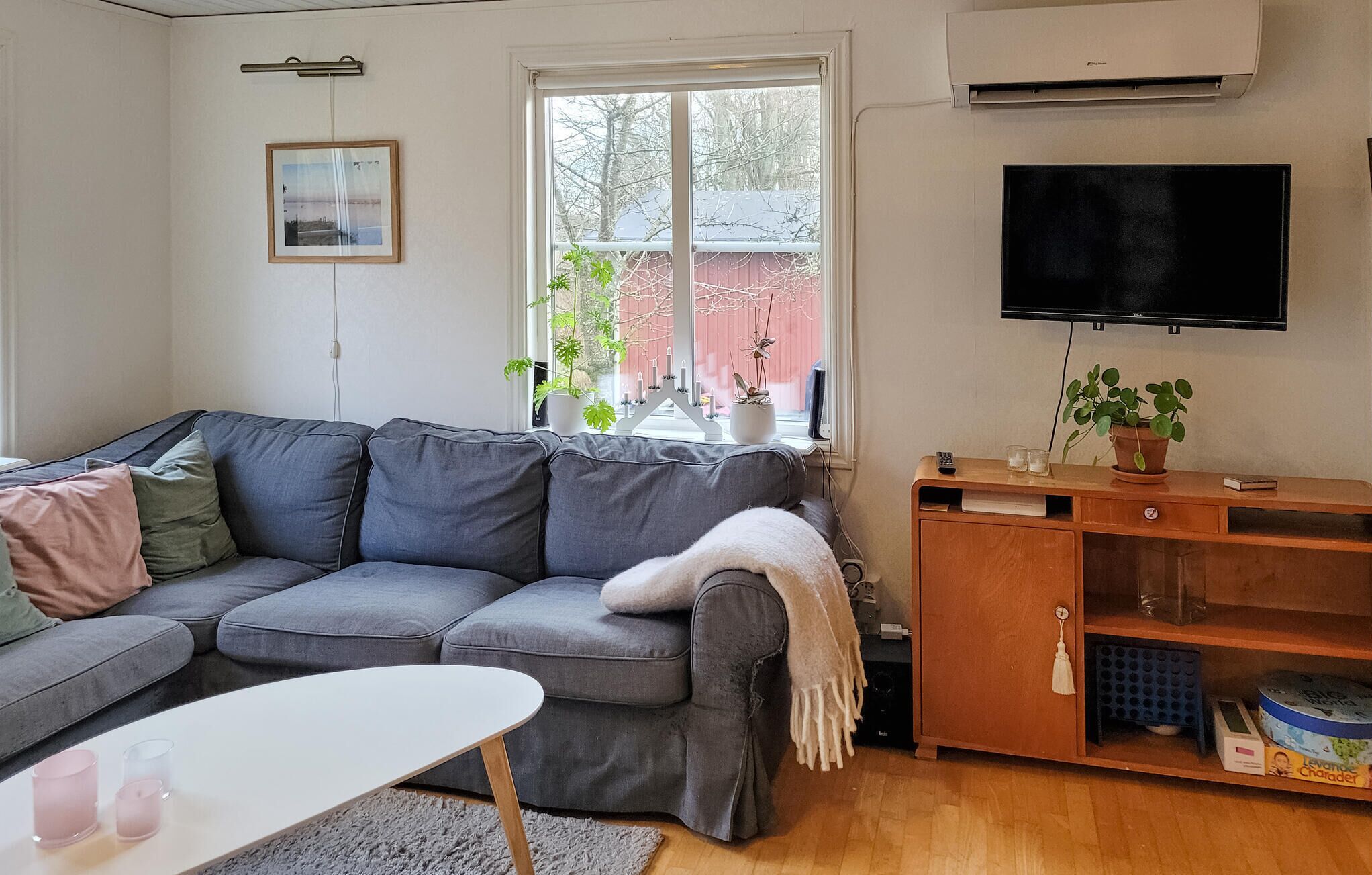 A living room with a grey sofa, a white coffee table, and a wooden cabinet with a TV above it.