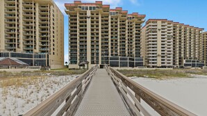 Una passerella che conduce a una spiaggia, con edifici a grattacielo sullo sfondo.