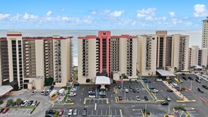 Un hotel di grandi dimensioni con numerosi piani, un parcheggio antistante e vista sull'oceano.