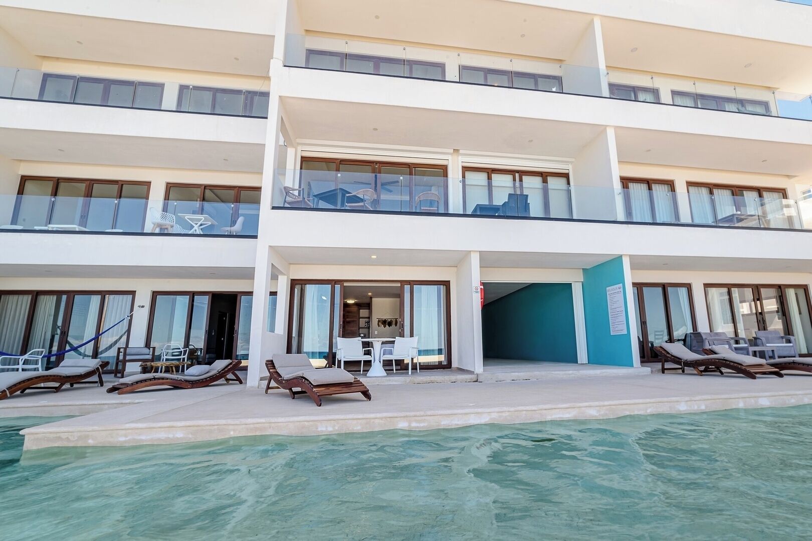 A multi-story hotel with a pool area, outdoor seating, and a covered patio.