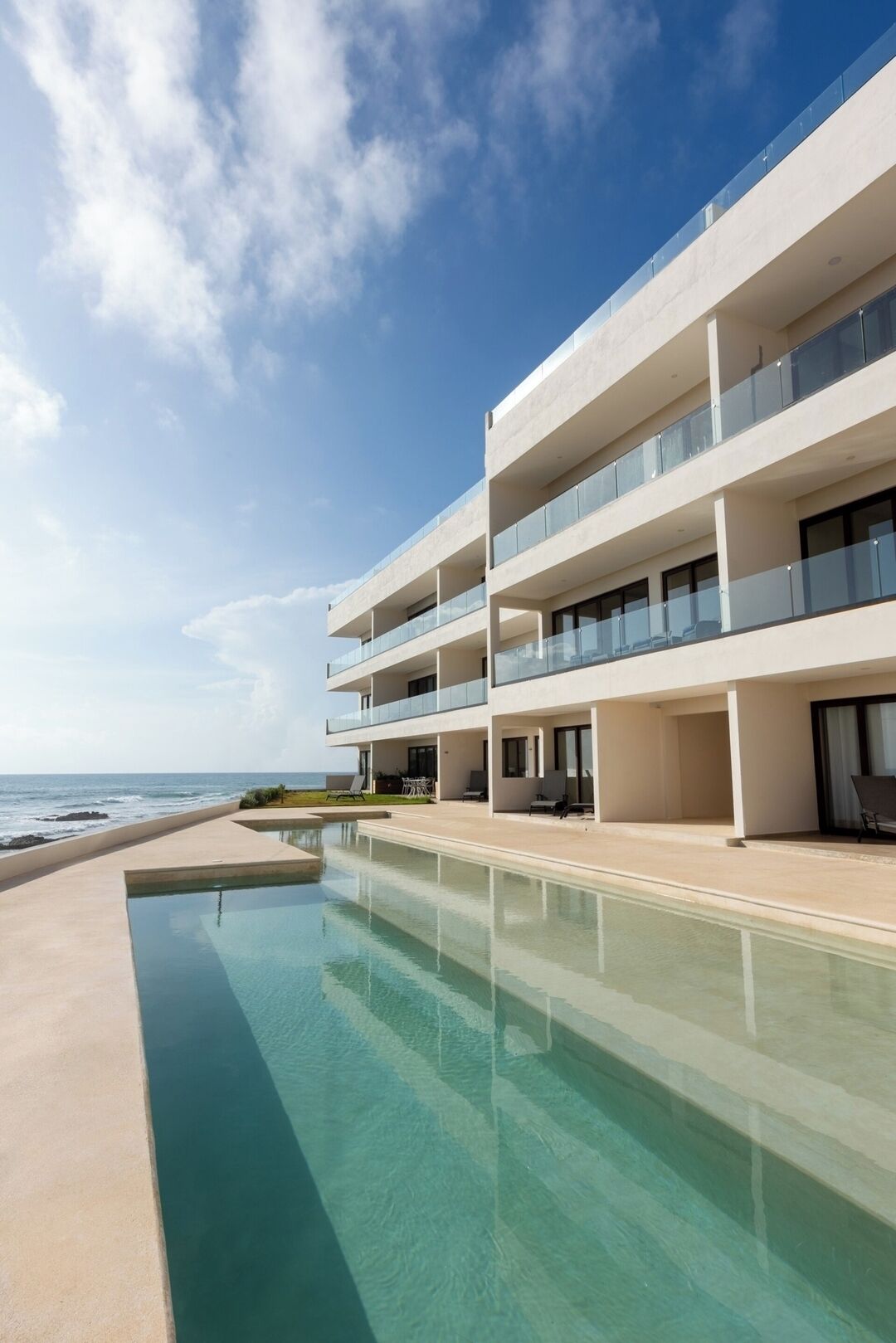 Um hotel moderno com piscina e vista para o oceano.