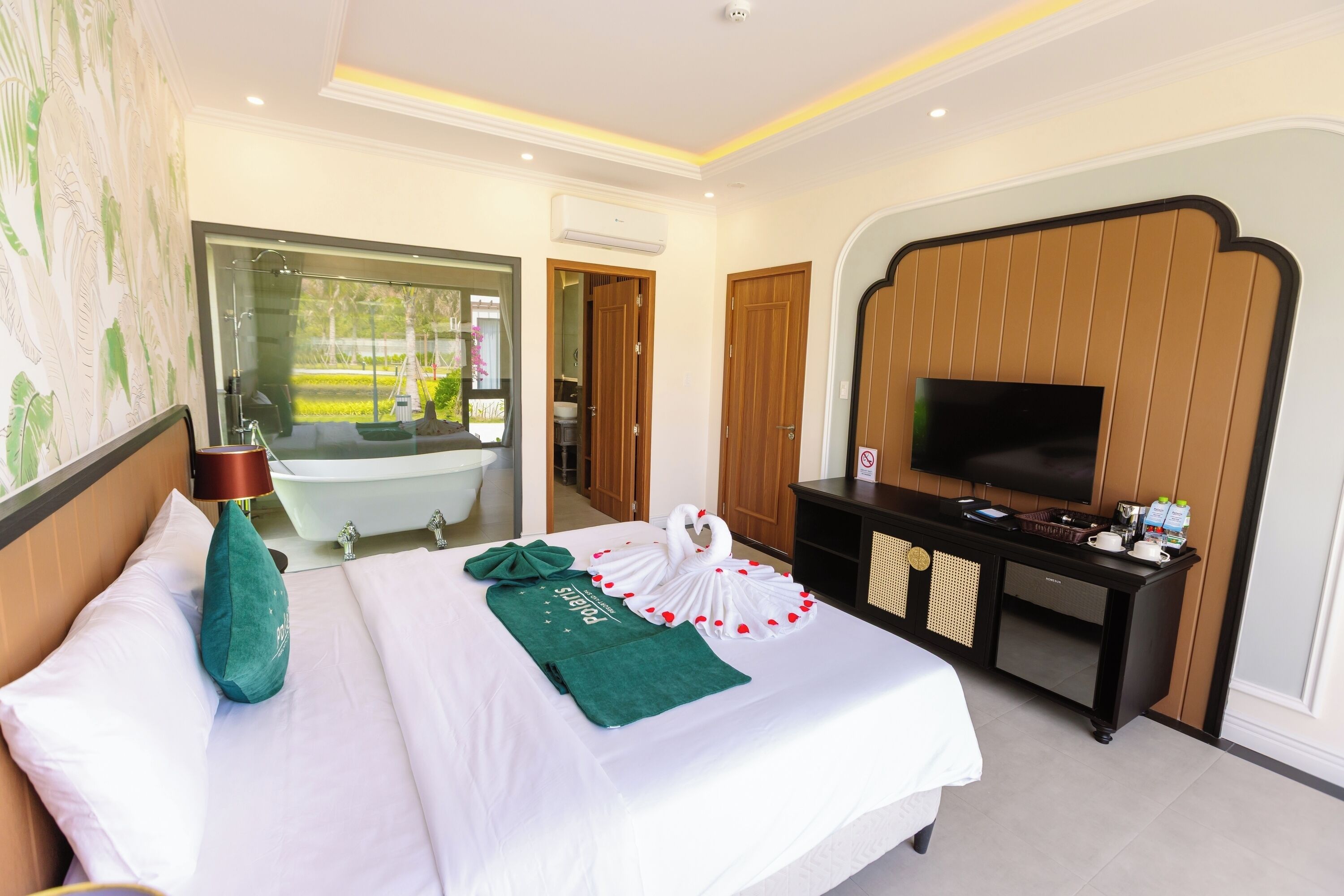 A hotel room with a bed, a TV, a desk, a bathroom, and a view of the outside.