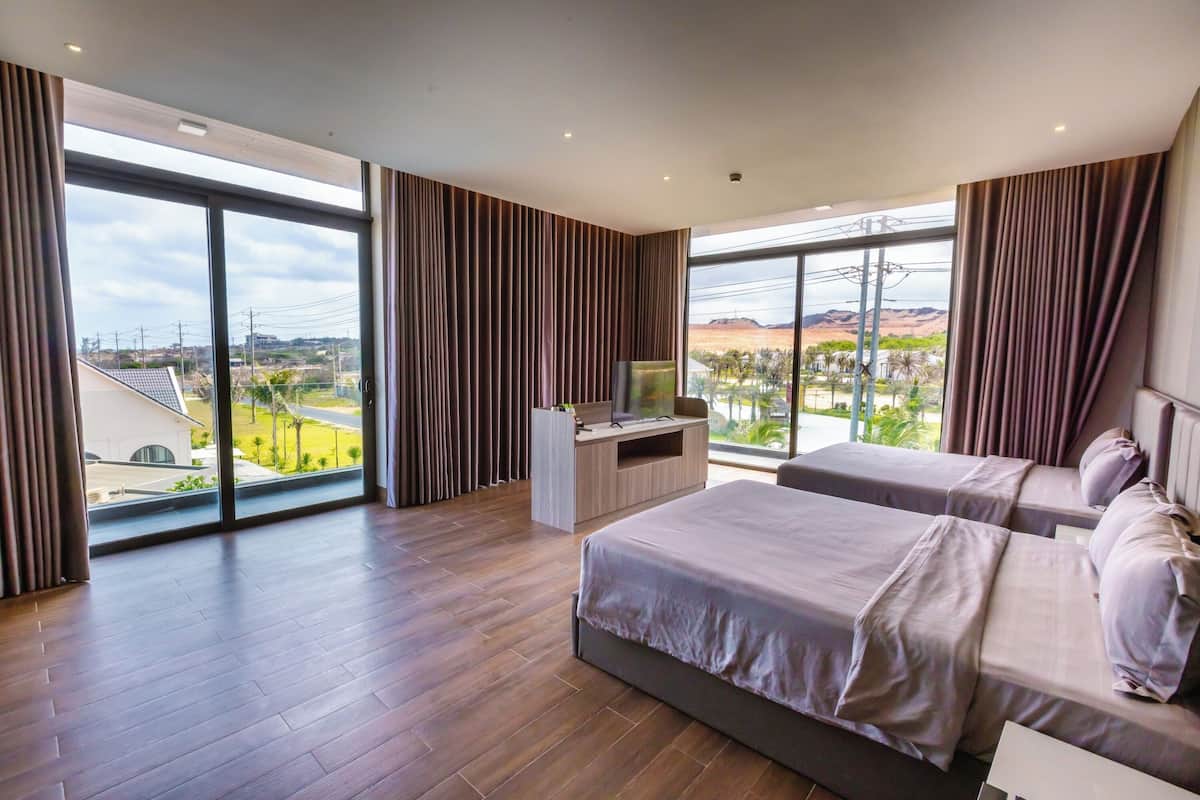 Camera d'albergo con due letti, una TV e un'ampia finestra vista sul paesaggio.
