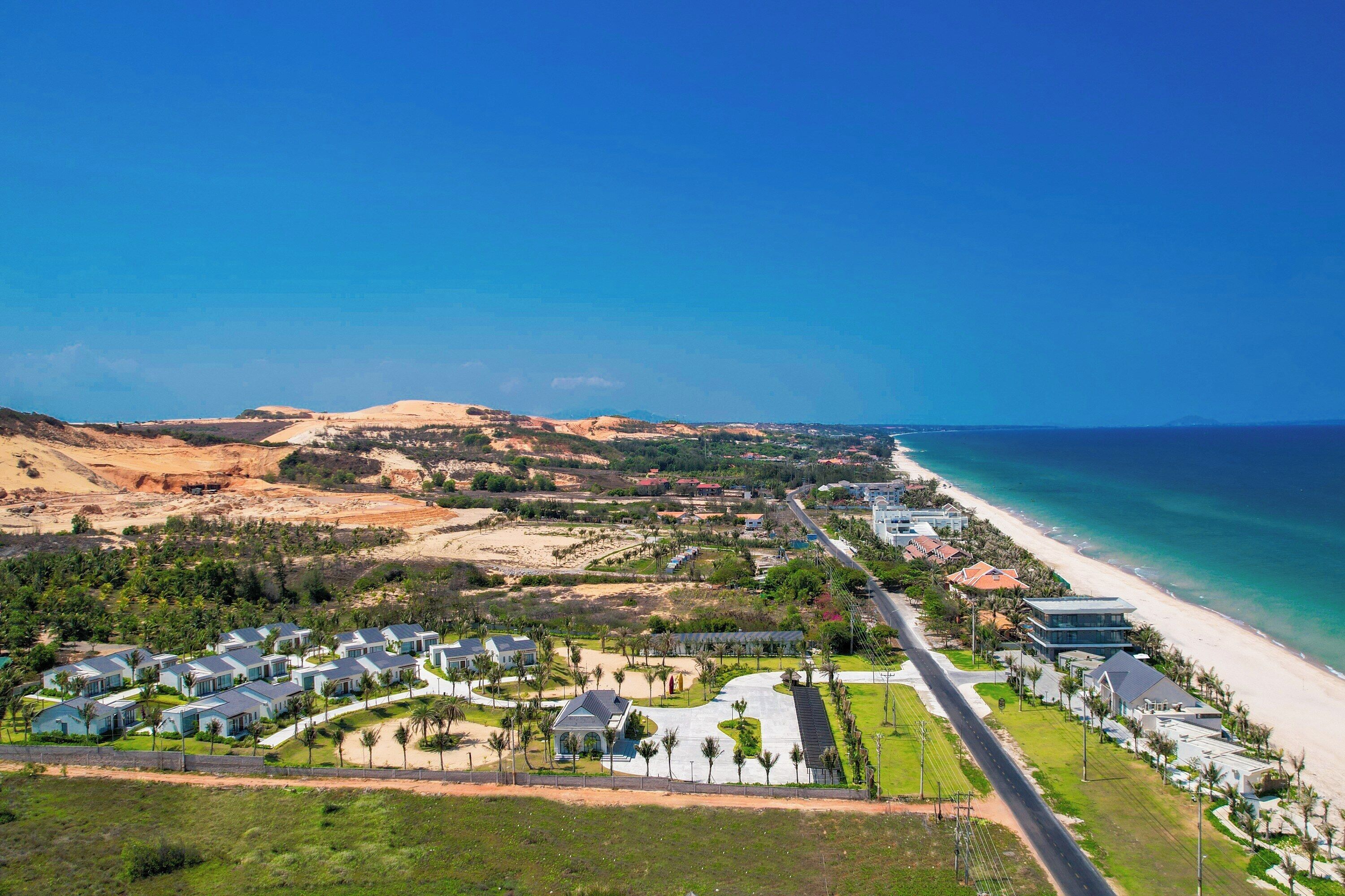 A coastal resort with beachfront villas, a main road, and a clear view of the ocean.