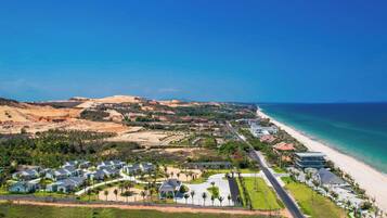 A coastal resort with beachfront villas, a main road, and a clear view of the ocean.