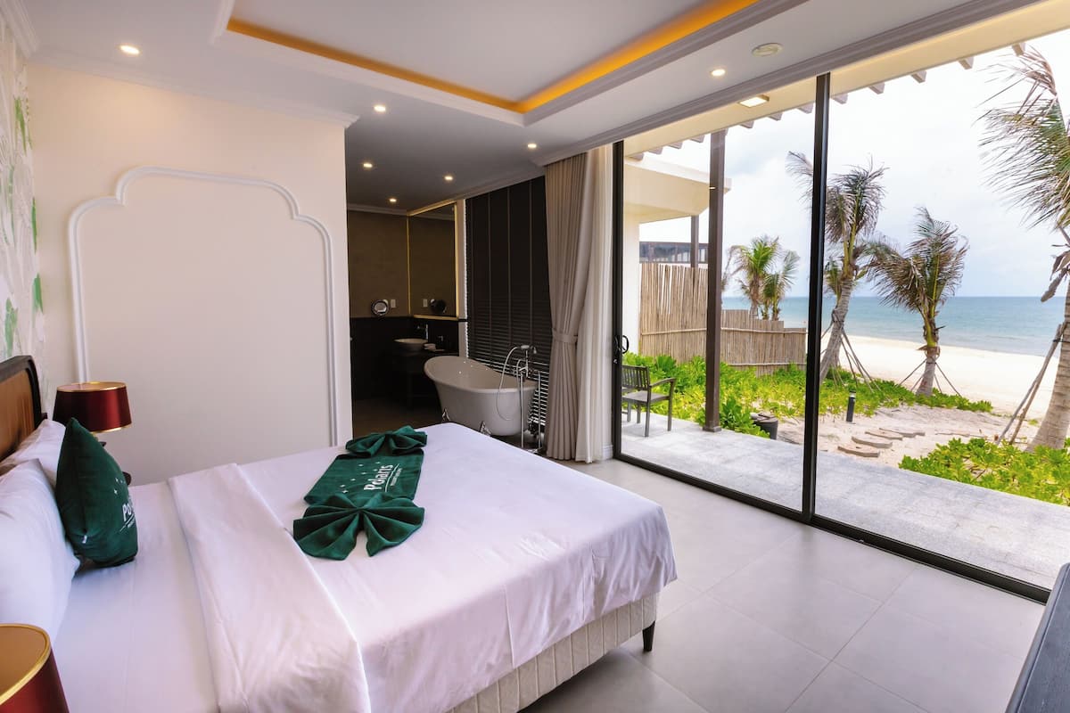 Una camera d'albergo con un letto, un bagno e vista sulla spiaggia.