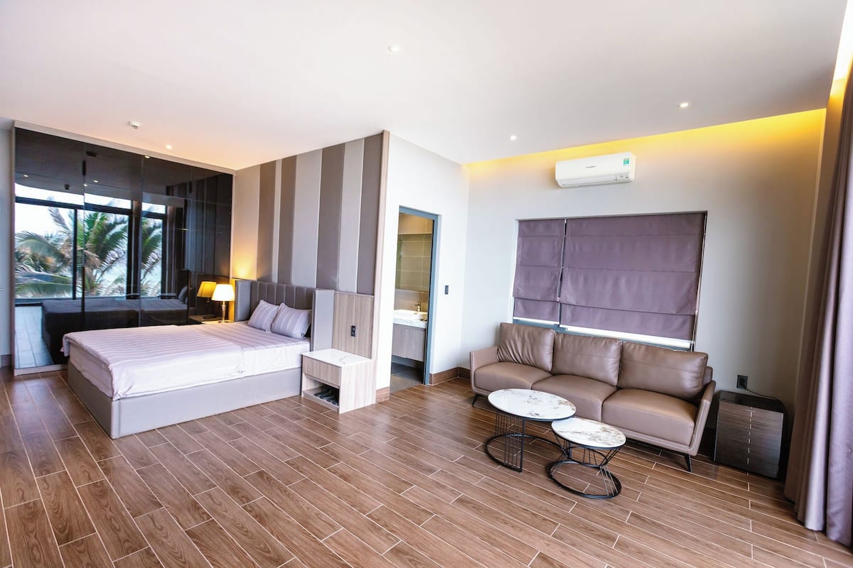 Una moderna camera d'albergo con un letto grande, un divano, un tavolino e una finestra con tende.
