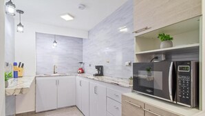 A modern kitchen with white cabinets, a marble backsplash, a built-in microwave, and a refrigerator. - 2bedroom with pooltable 1 block -Lleras  (Medellín)