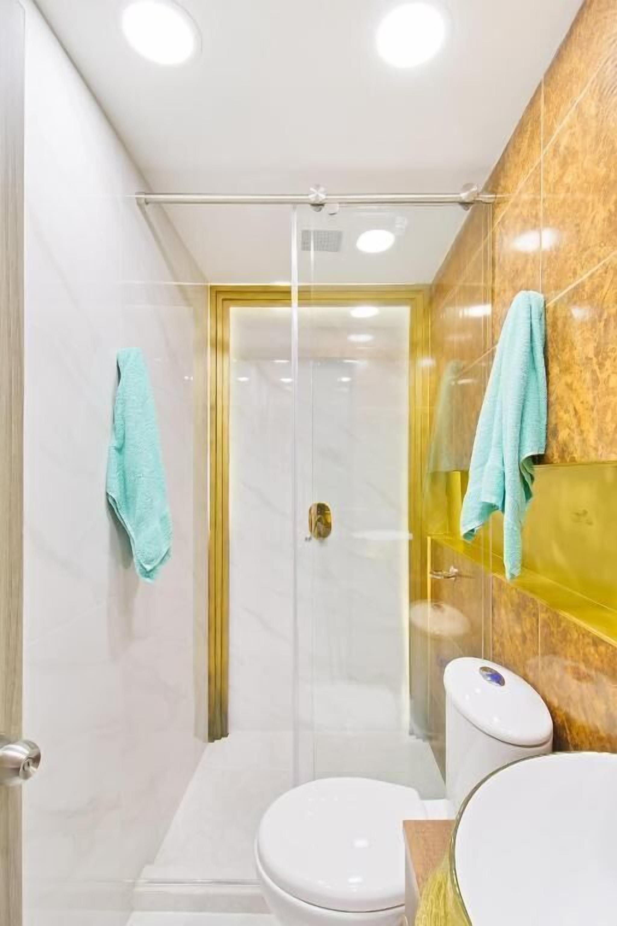Une salle de bain moderne dotée d’une douche à parois de verre, de toilettes et d’un lavabo avec un plan de travail en marbre.